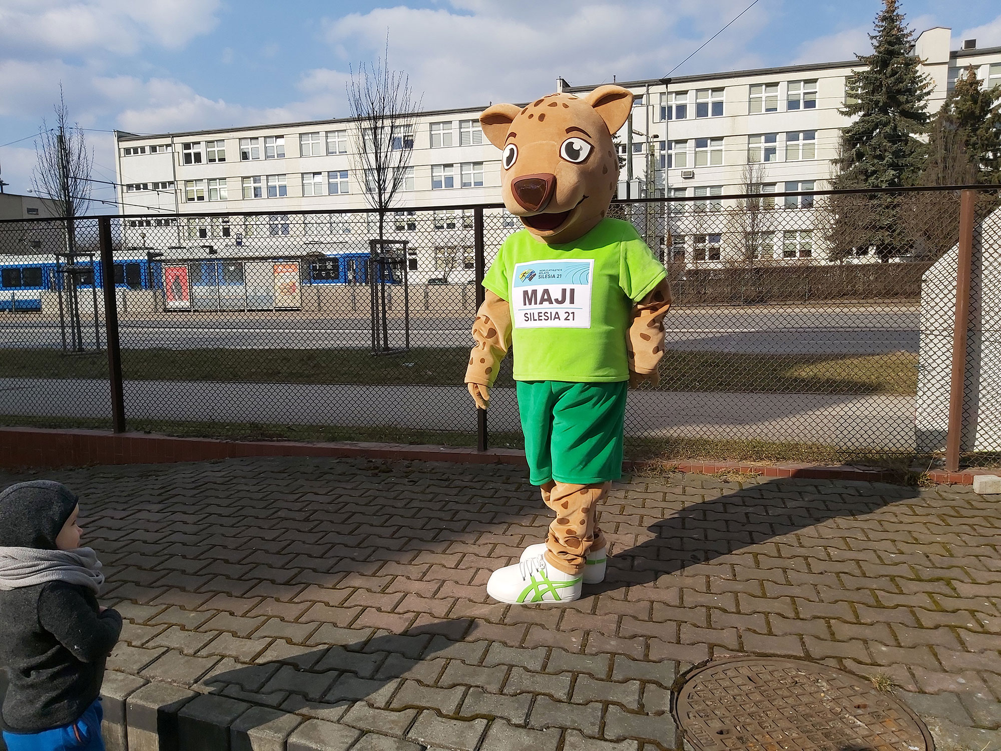 Na fotografii widnieje przebranie w postaci geparda pozujące do zdjęcia przed siedzibą firmy Elabika